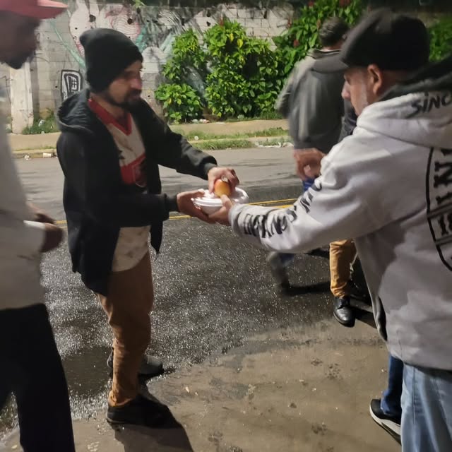 Voluntário entregando um prato de comida na rua